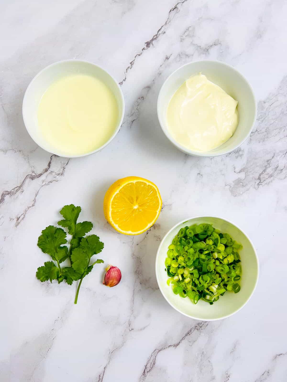 Ingredients to make green onion dip on a marble surface.