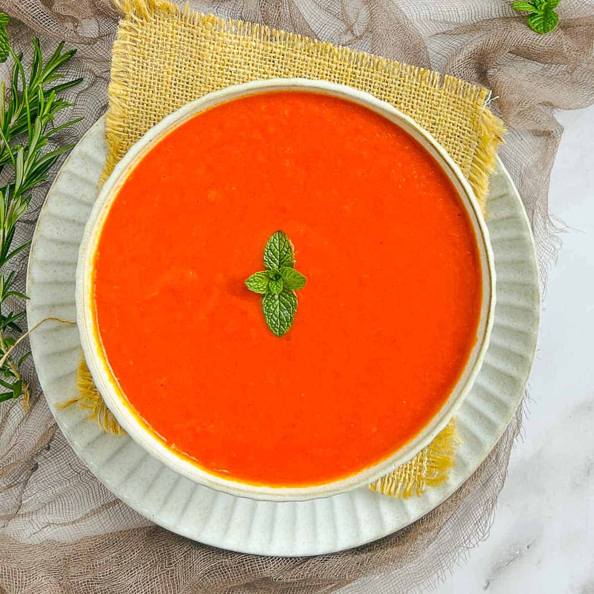 Roasted bell pepper and habanero sauce in a white bowl topped with a mint leaf.