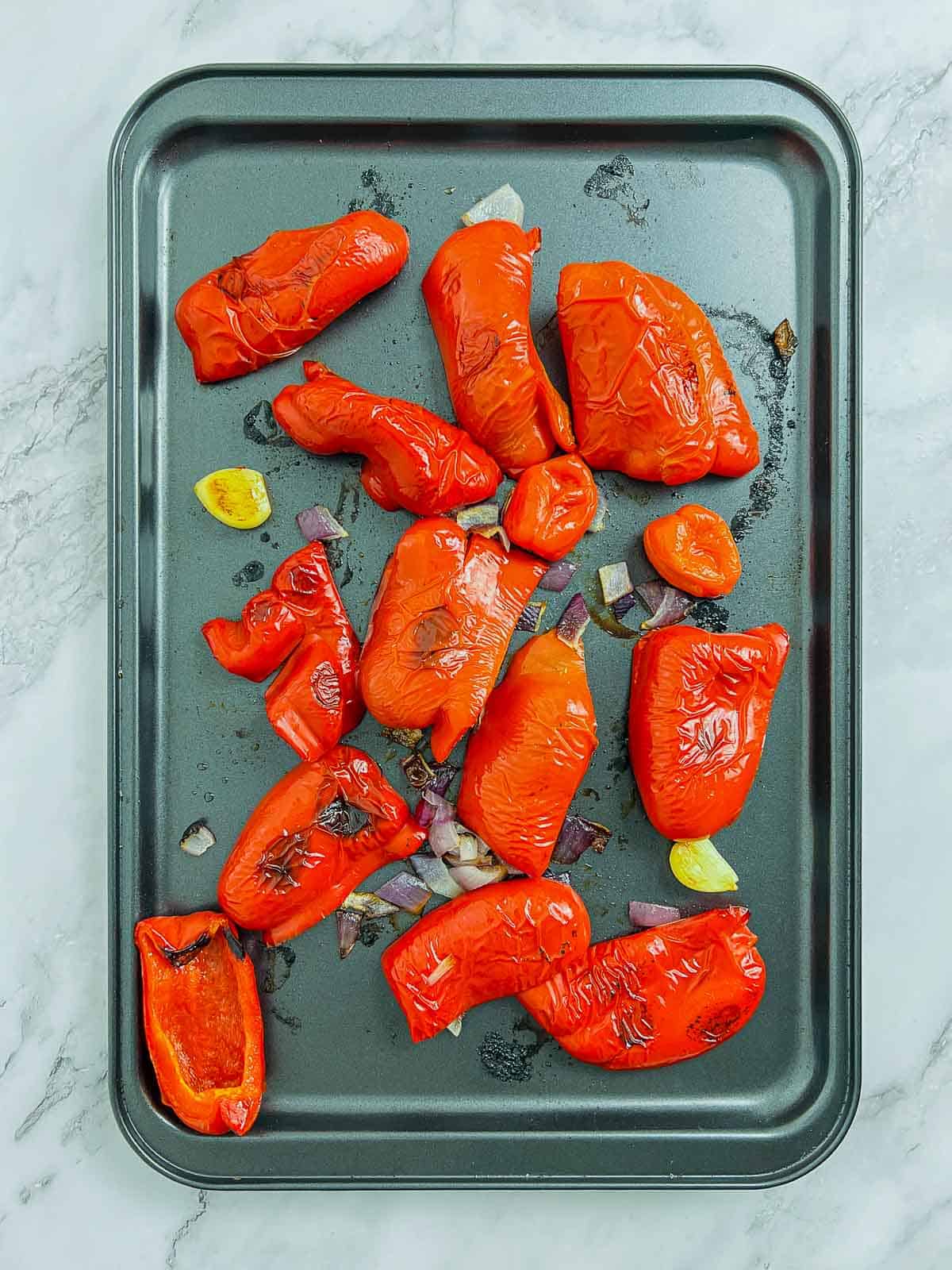 Roasted peppers, habanero, onion, and garlic on baking sheet.