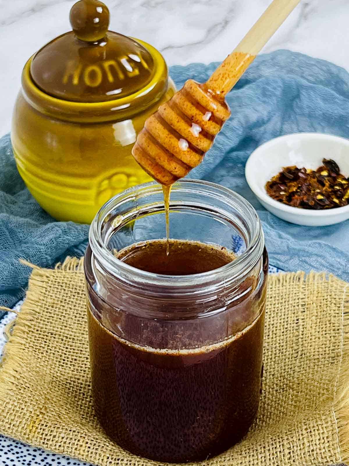 Hot honey in a mason jar with a honey pot in the background.