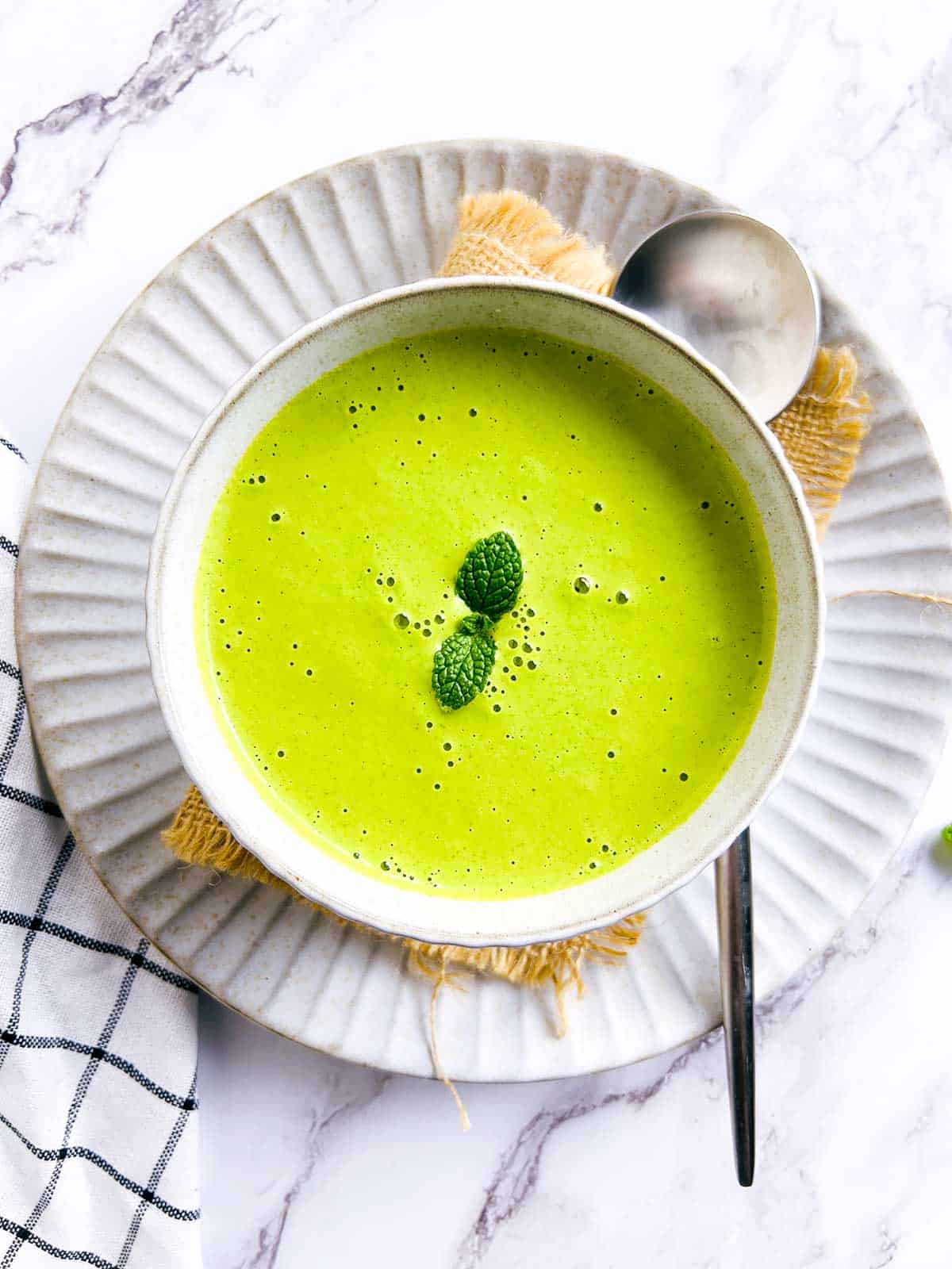 Mint and peanut chutney in a white bowl with a spoon in the background.