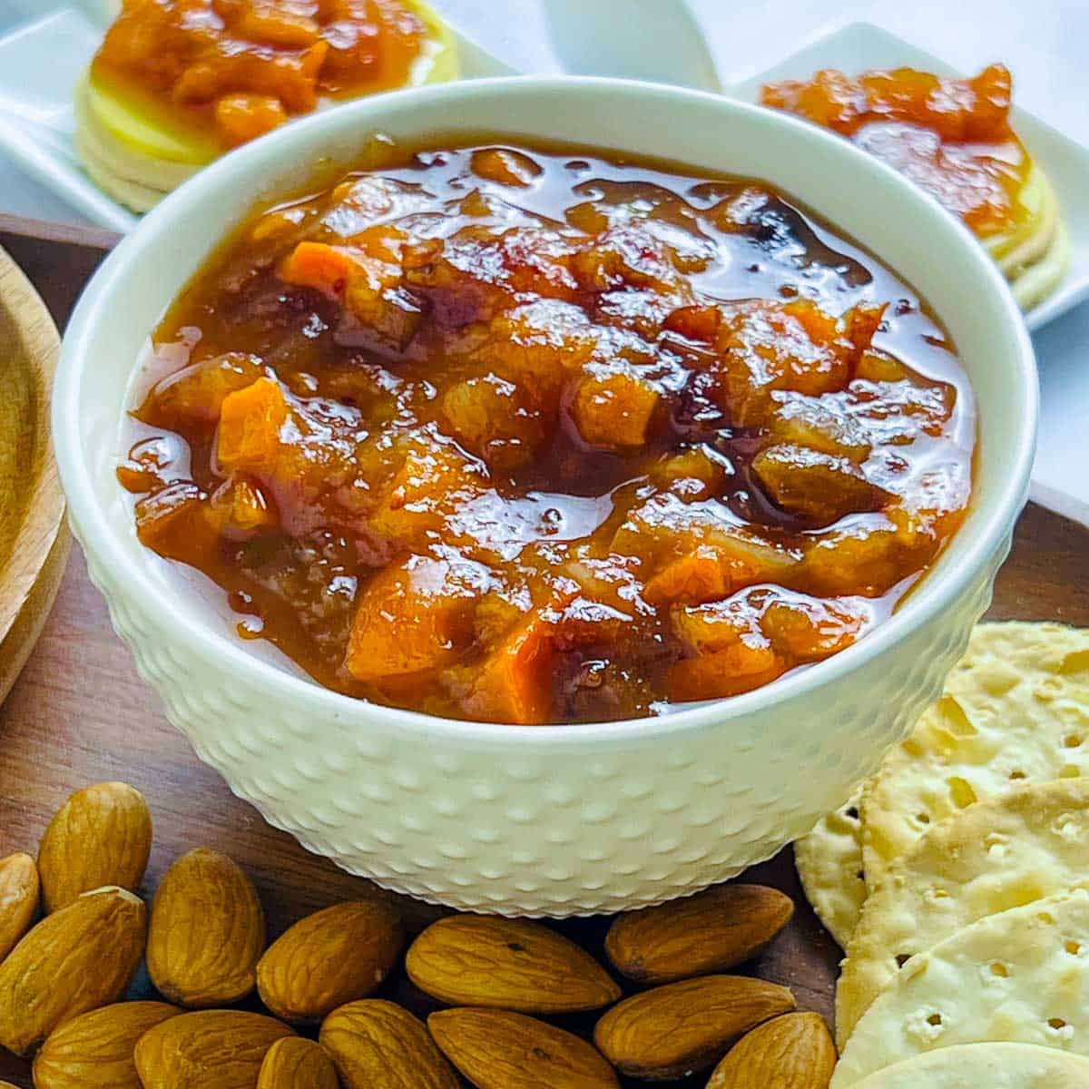 Persimmon cranberry chutney in a white bowl with almonds in the background.