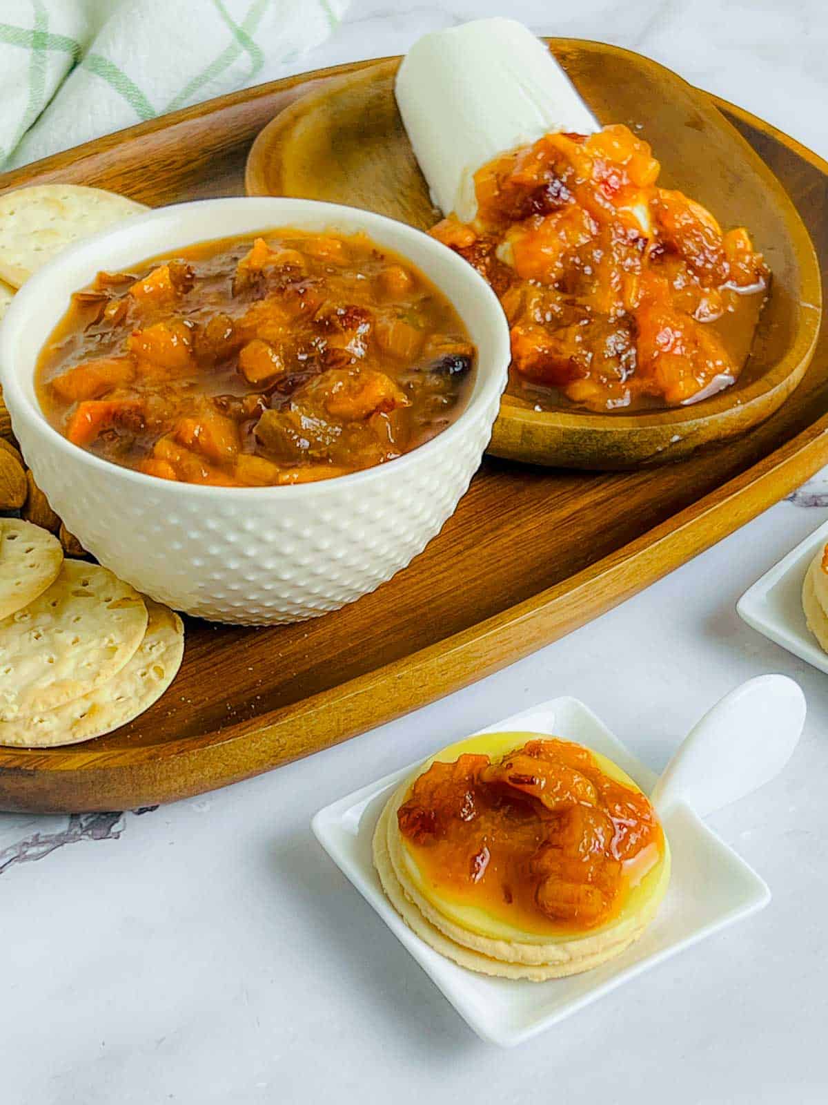 Persimmon chutney in a white bowl placed on a wooden tray.