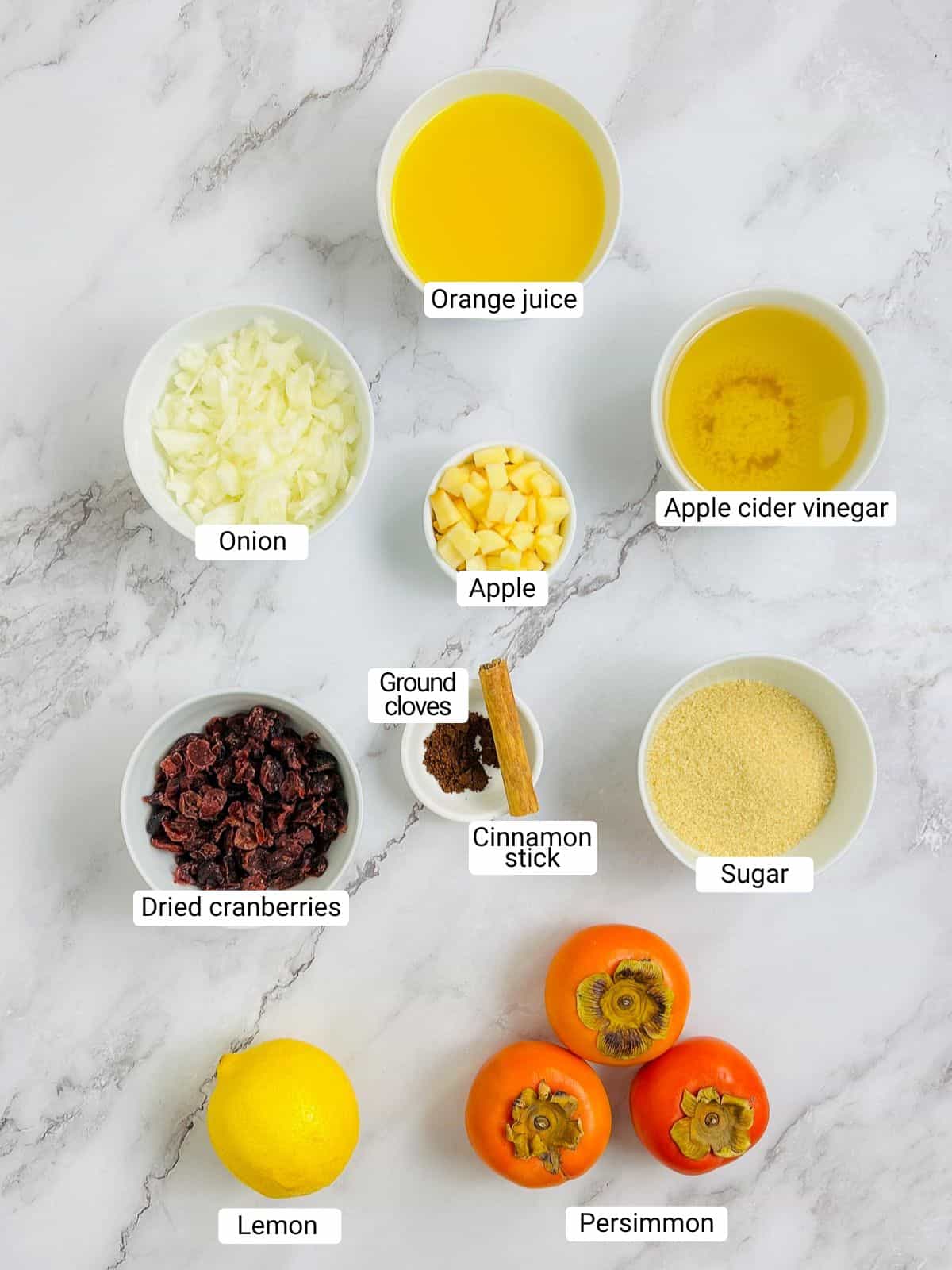 Ingredients to make persimmon chutney on a marble surface.