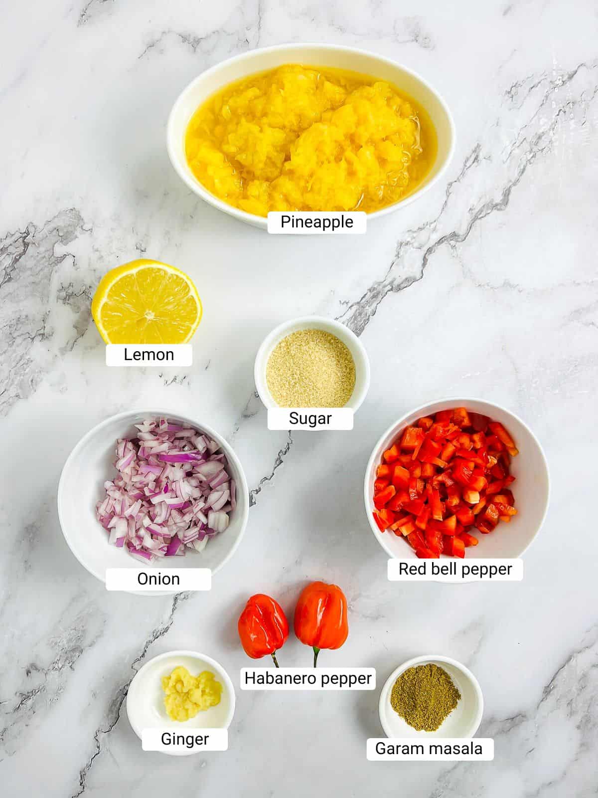 Ingredients to make pineapple habanero chutney on a marble surface.