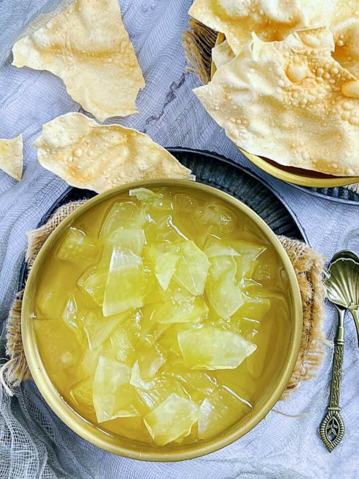 Plastic chutney in a brass bowl served with papad.