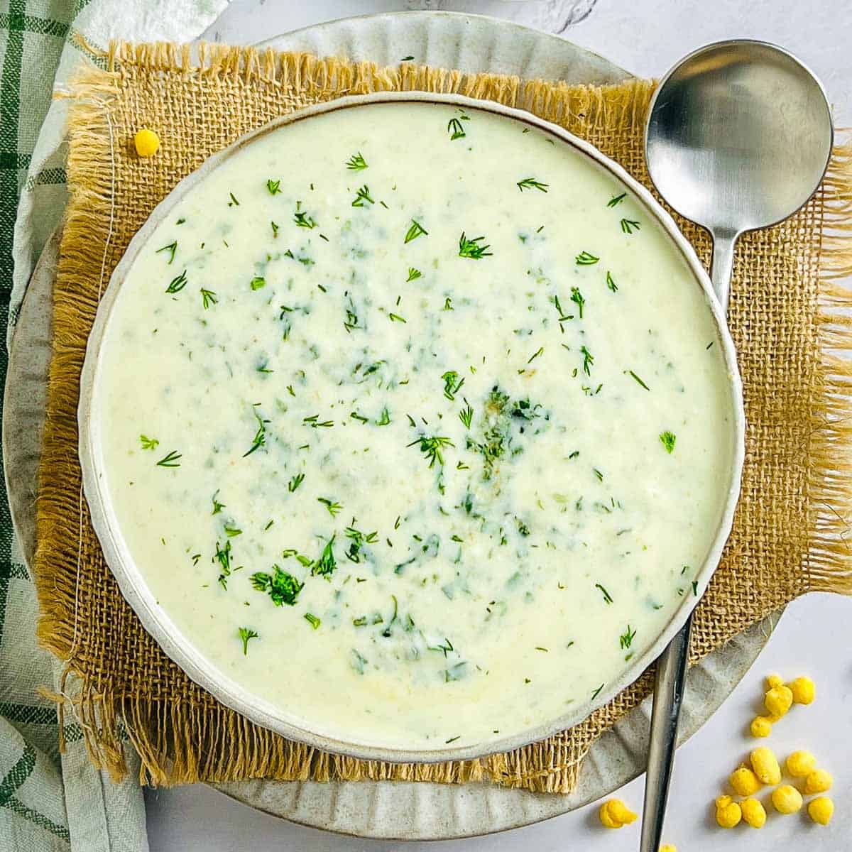 Spinach dill raita in a white bowl with a spoon in the background.