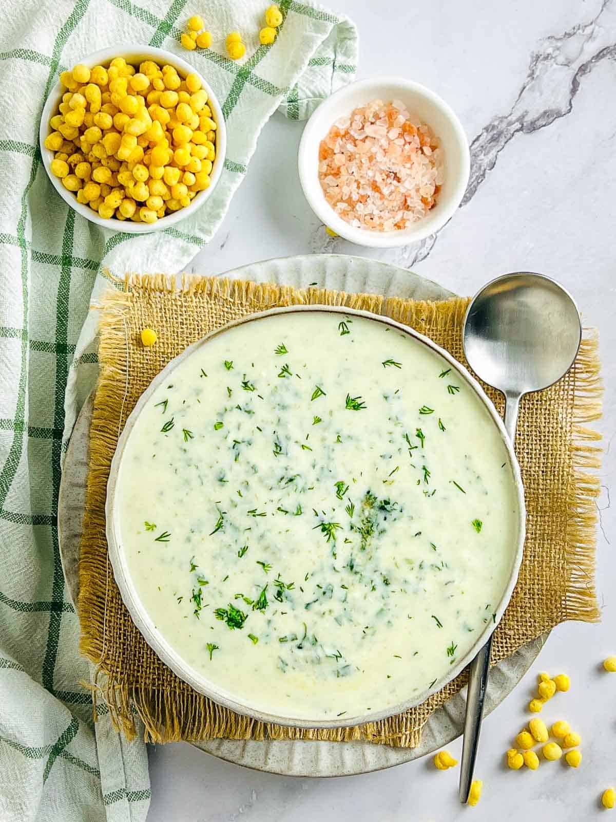 Spinach dill raita in a bowl with boondi and salt in the background.