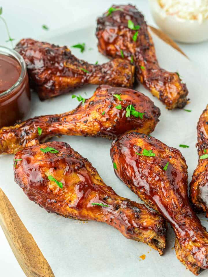 BBQ chicken placed on a parchment paper over a wooden board.