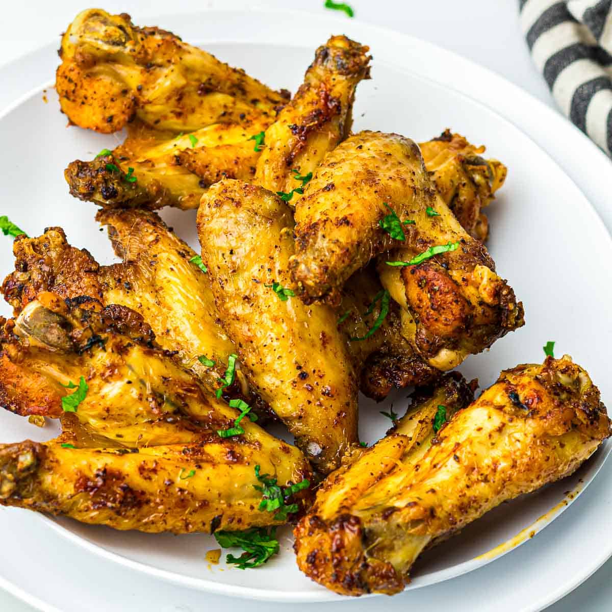 Air fryer chicken wings on a white plate garnished with parsley.