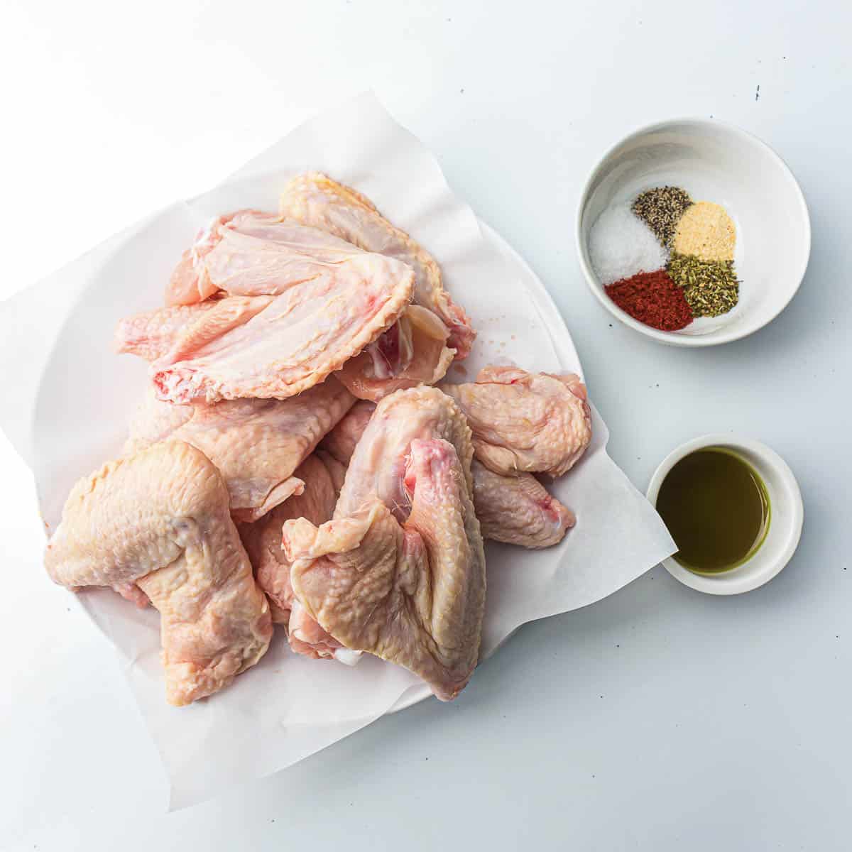 Ingredients to make chicken wings on a white surface.