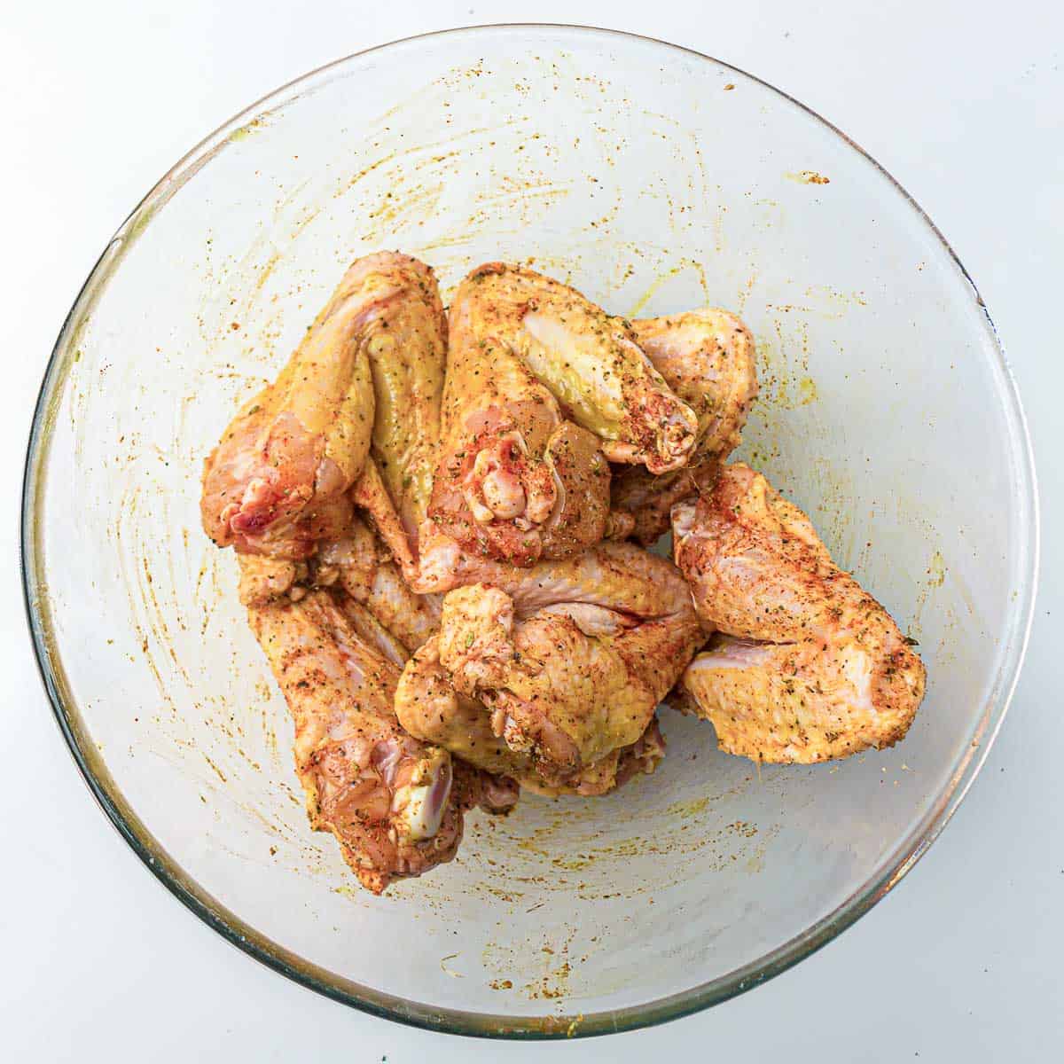 Seasoned chicken wings in a mixing bowl.