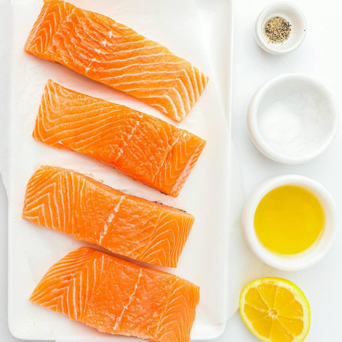 Ingredients to bake salmon on a white surface.