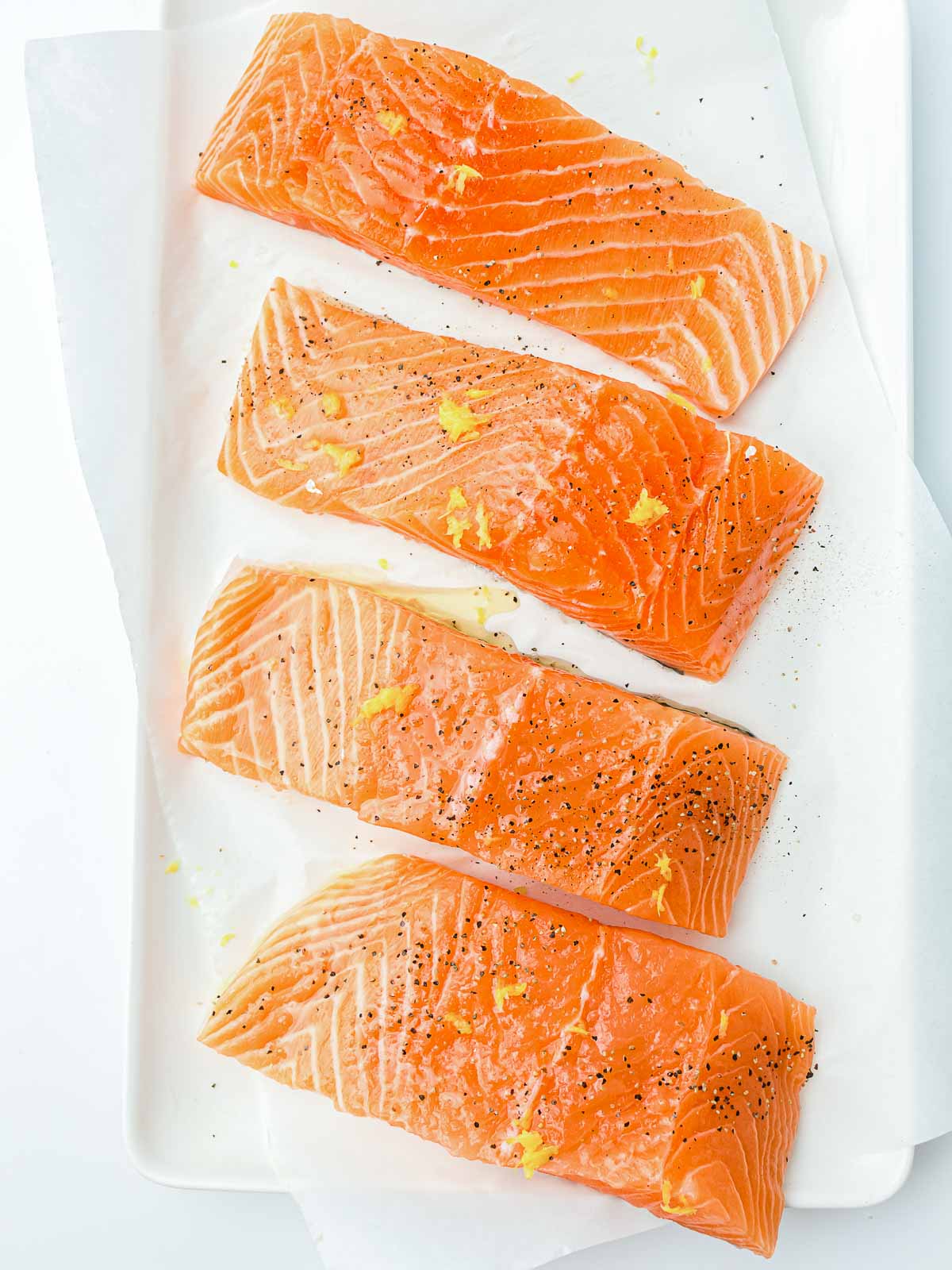 Seasoned salmon on a white rectangular plate.