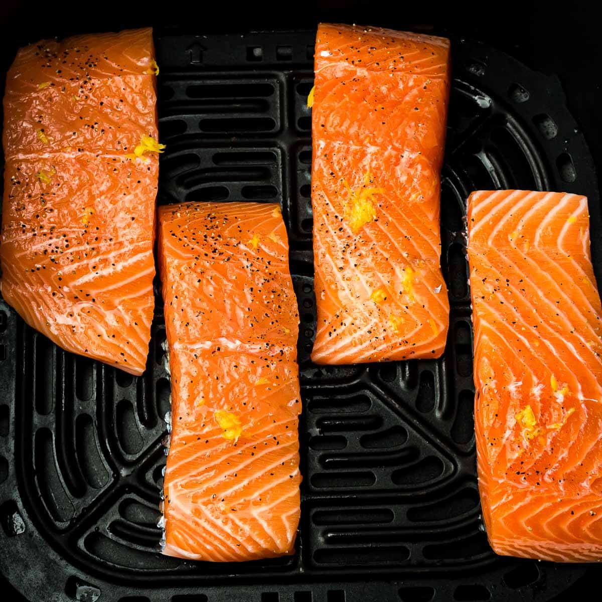 Salmon in a single layer in the air fryer basket.