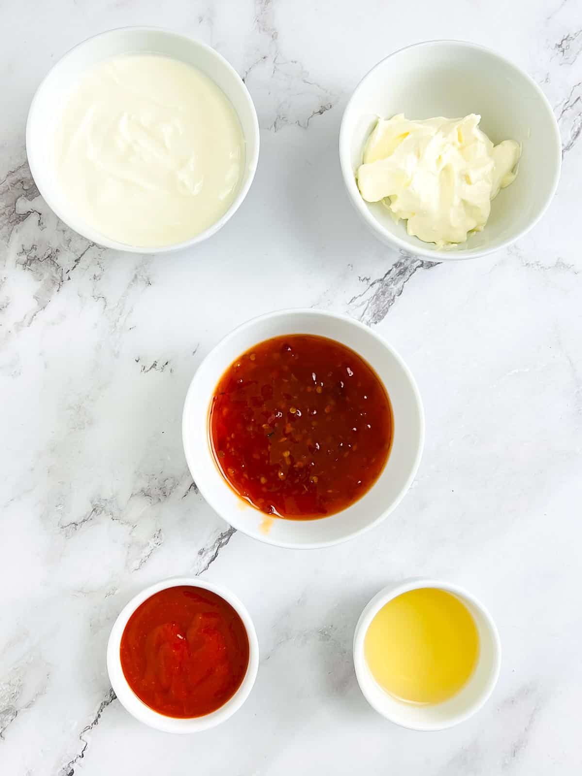 Ingredients to make bang bang sauce on a marble surface.