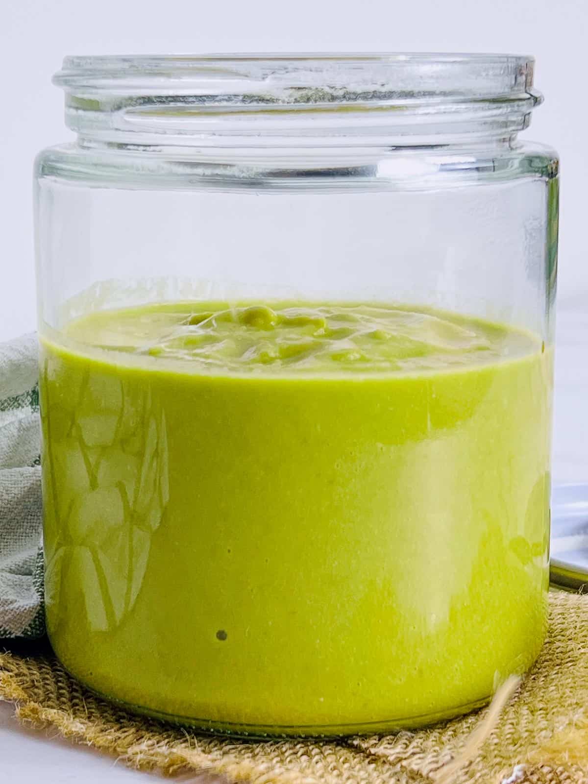 Green chili sauce stored in a glass jar.