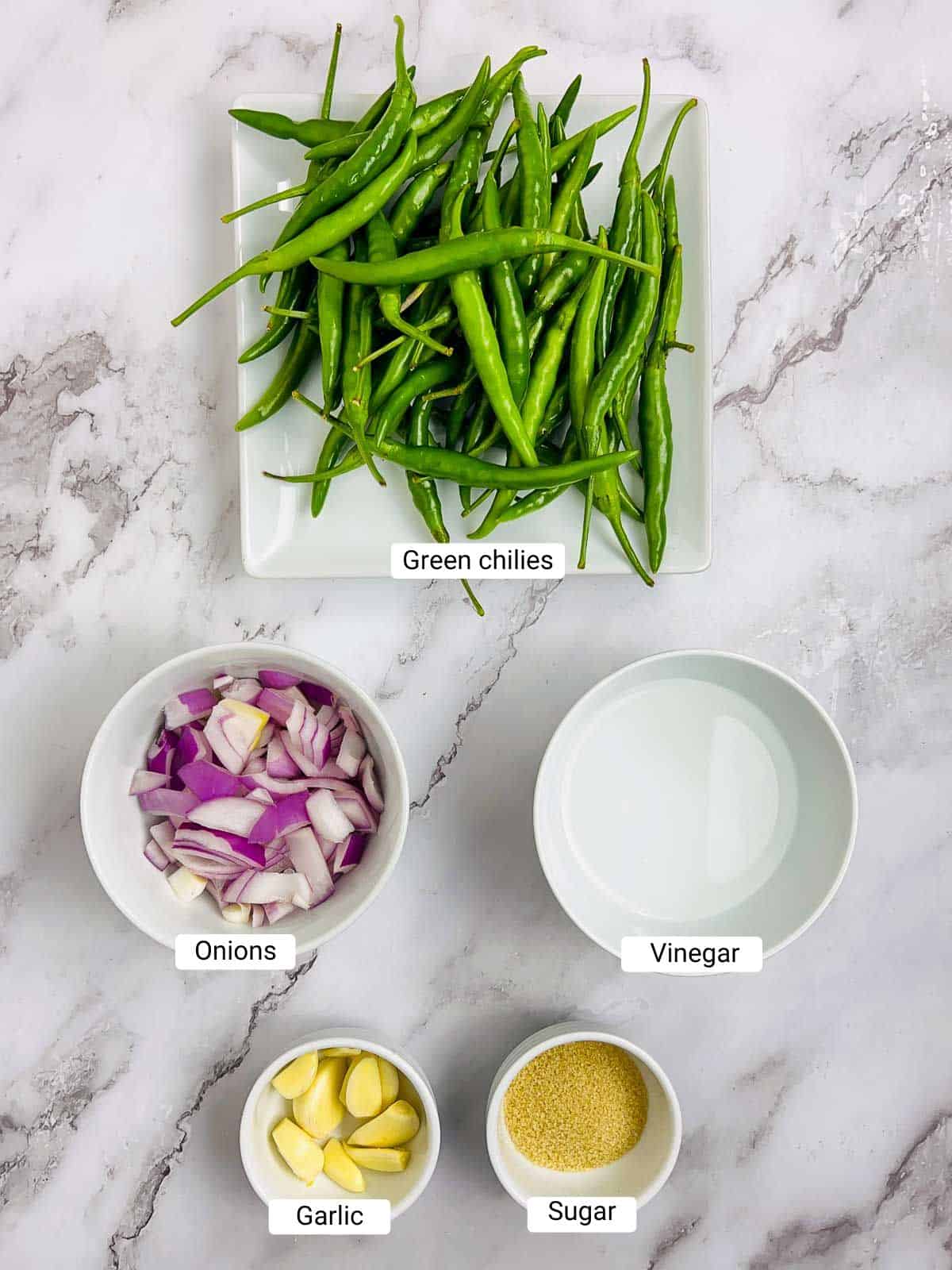 Ingredients to make green chili sauce on a marble surface.