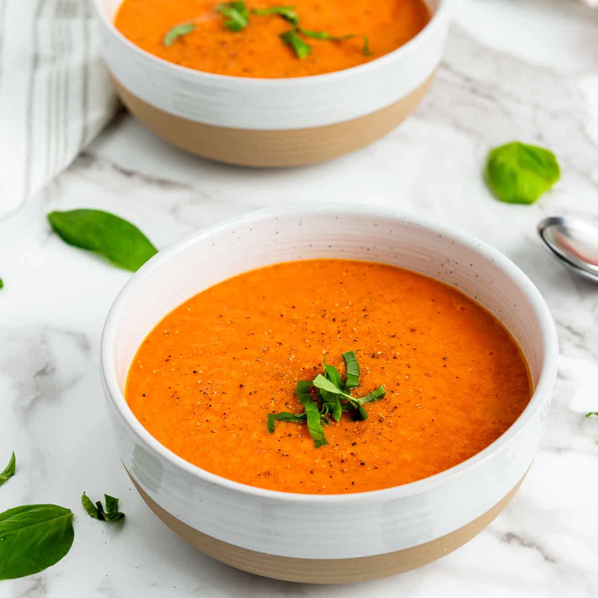 Tomato soup in a white bowl topped with basil.