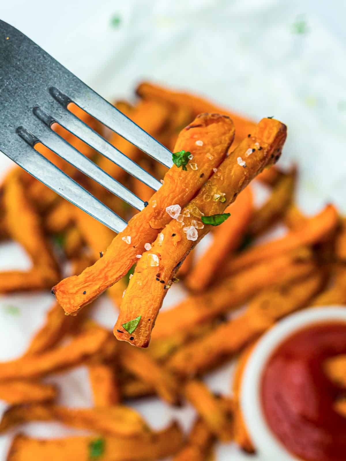 Two sweet potato fries on a fork.