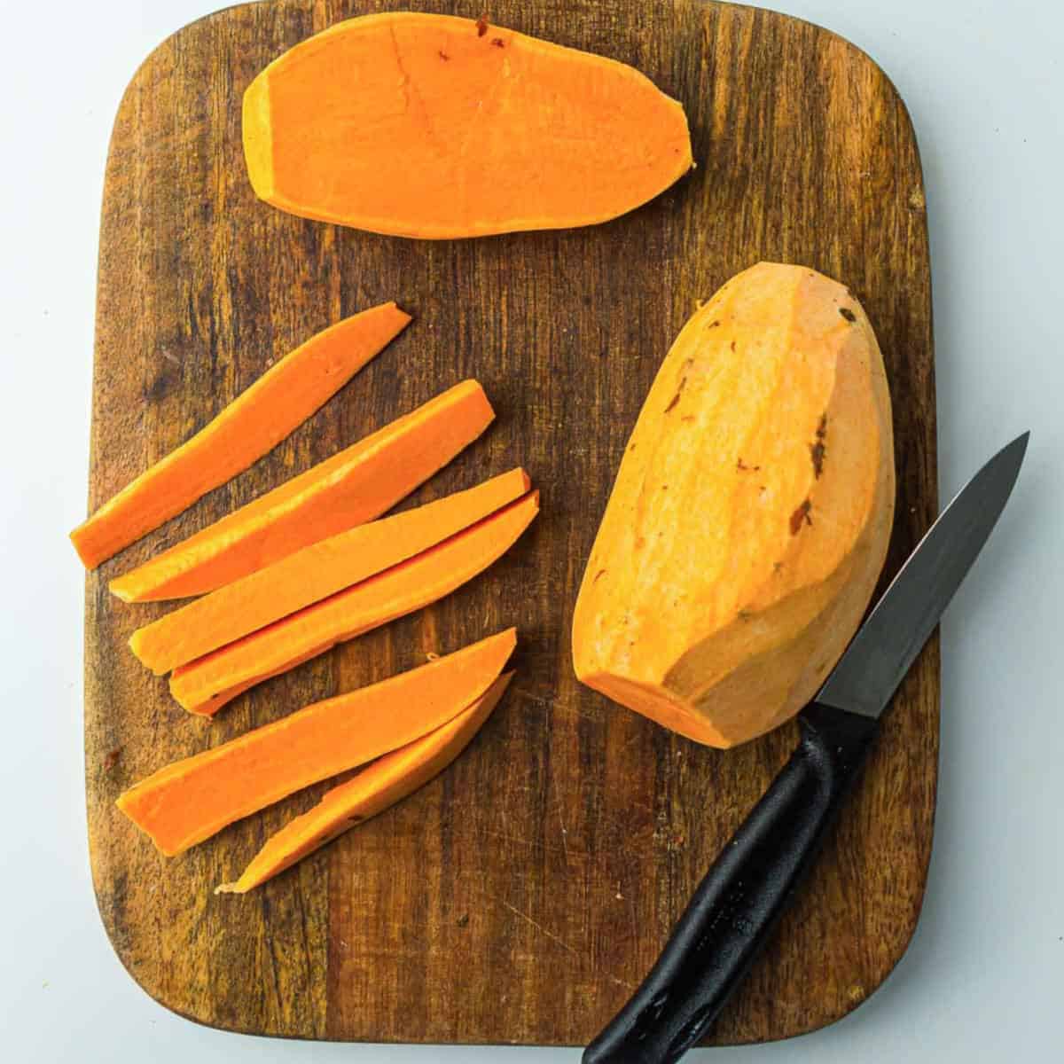 Peeled and cut sweet potatoes on a wooden board.