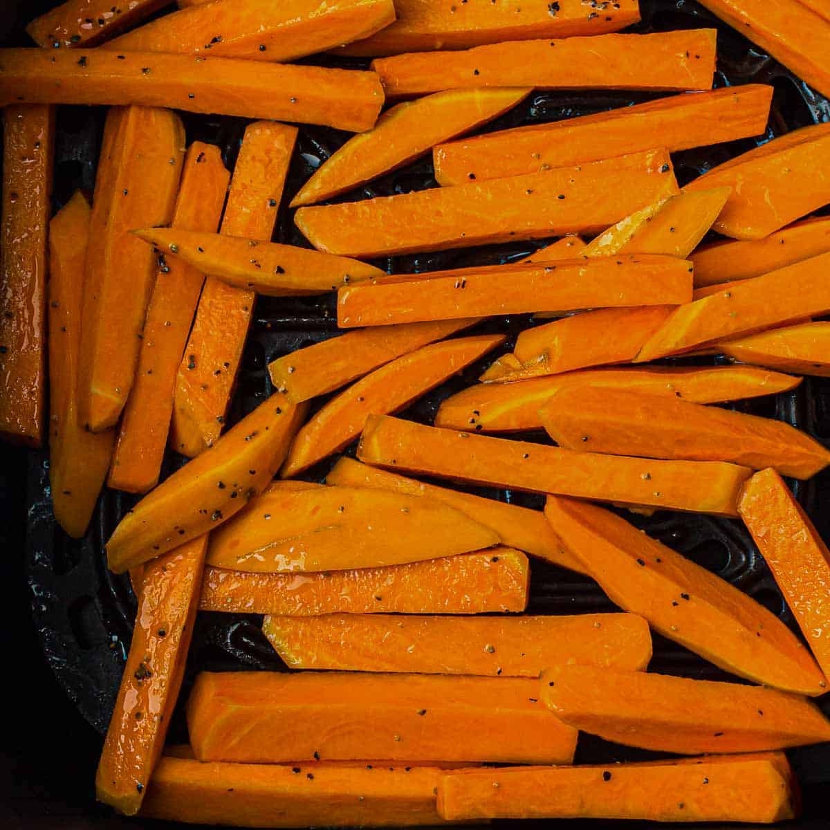 Spread seasoned fries in air fryer basket.