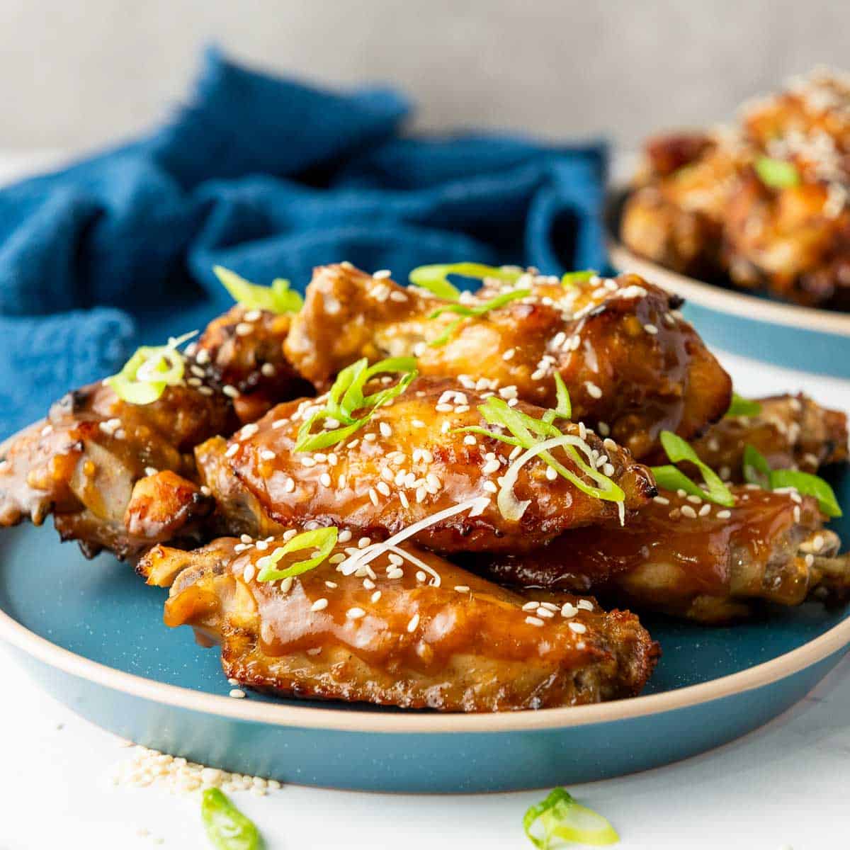 Side view of Asian sticky chicken wings on a blue plate.