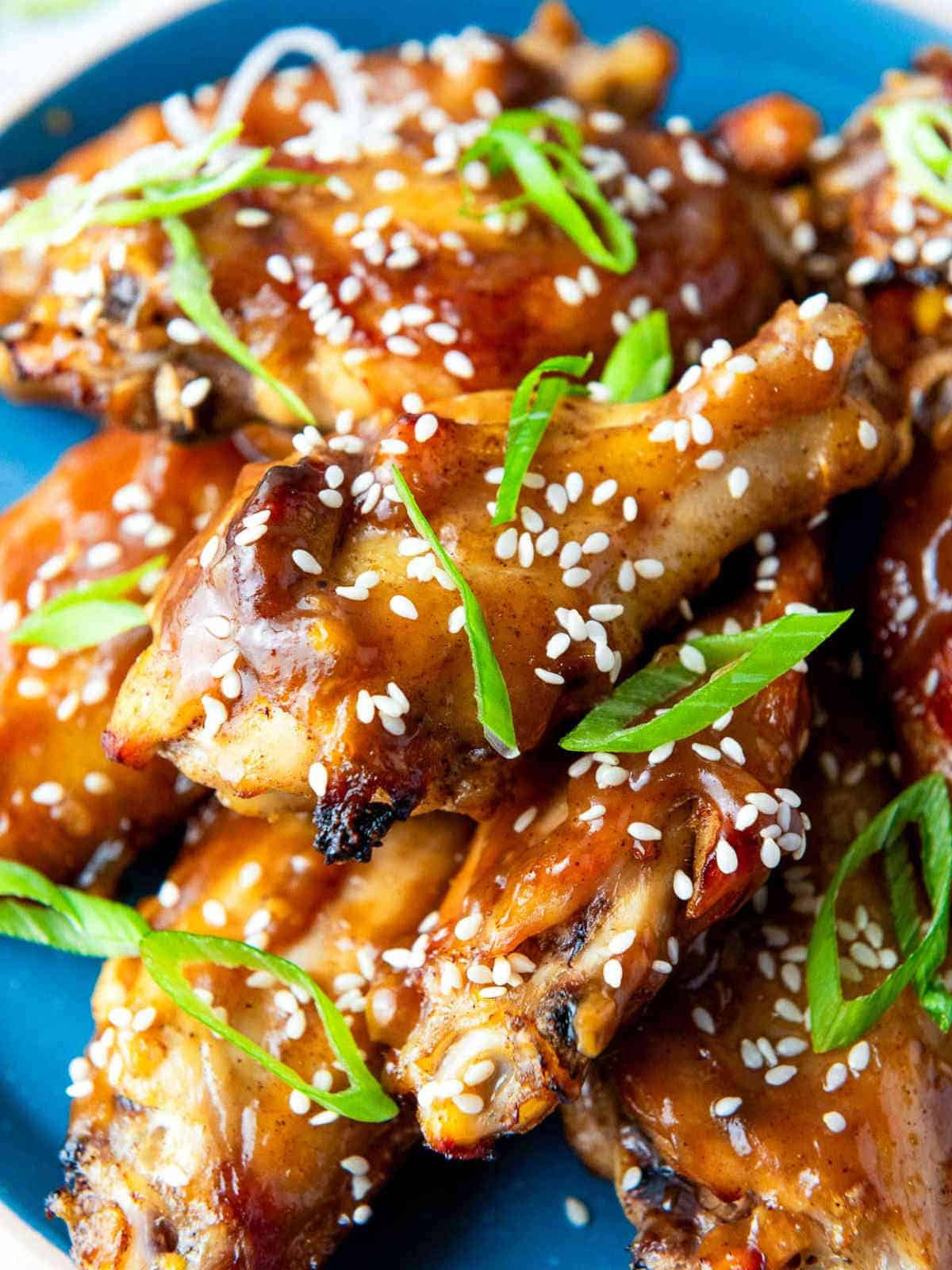 Sticky chicken wings garnished with green onions and sesame seeds.