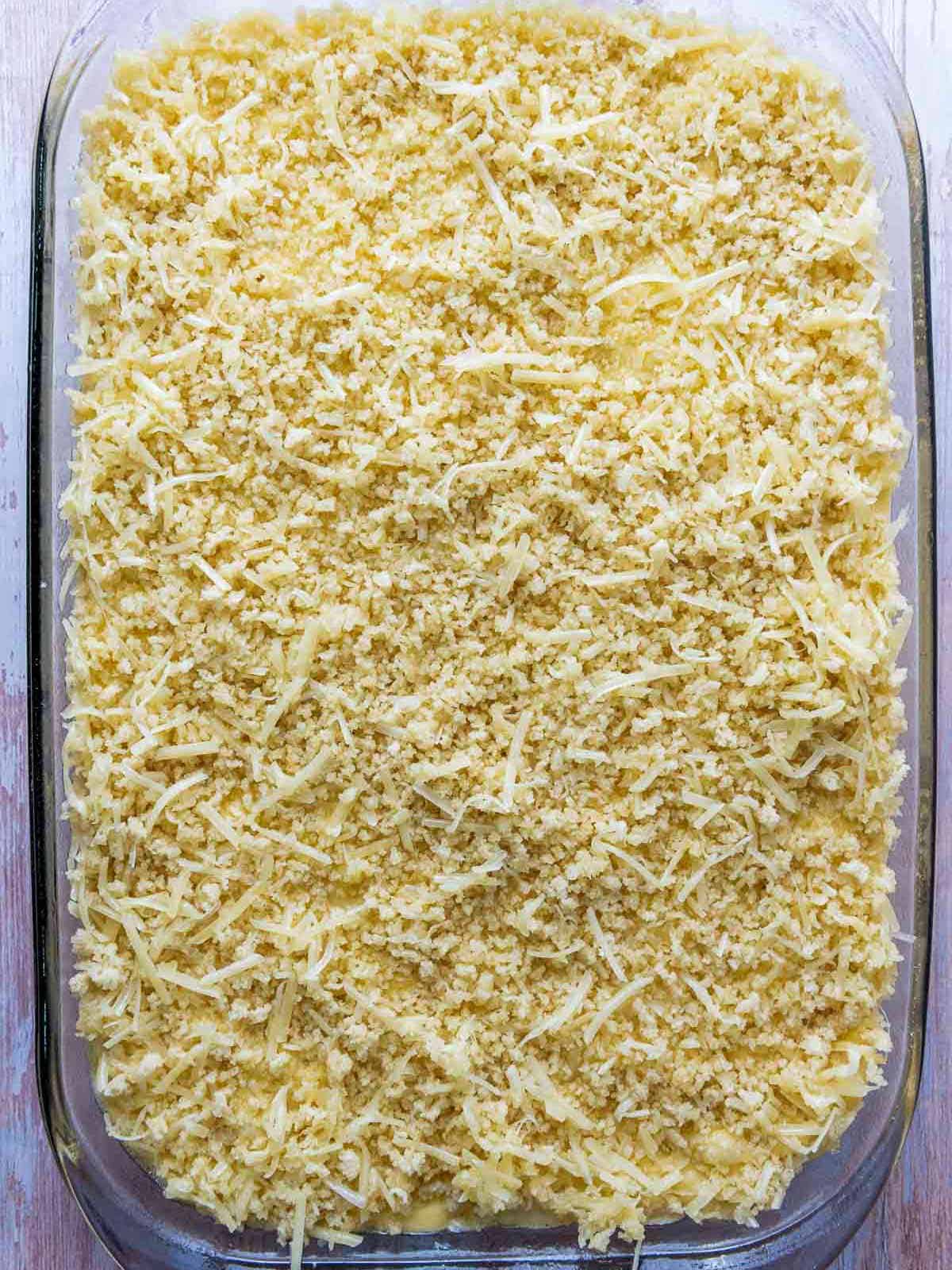 Topping spread on top of pasta in baking dish.