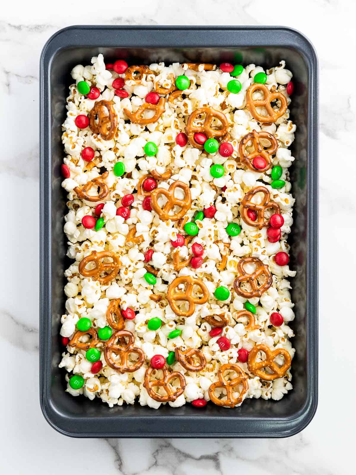 Popcorn, pretzels, and M&M on a baking tray.