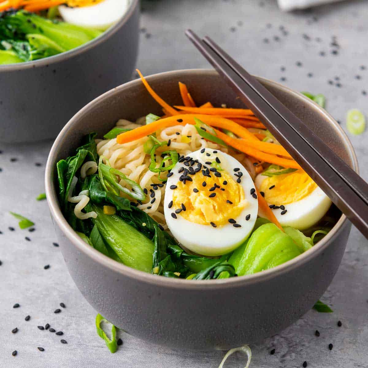 Elevated raman in a grey bowl with chopsticks on top.