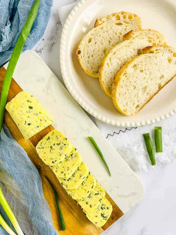 Scallion butter served with slices of fresh bread on a white plate.