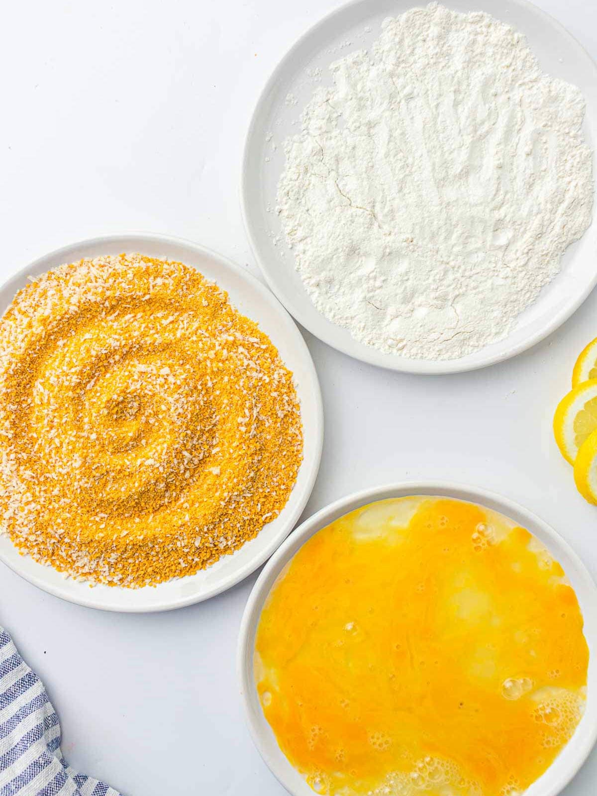 Eggs, flour, and breadcrumbs in separate plates.