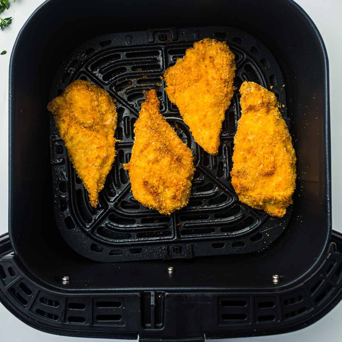 Cooked chicken in air fryer basket.