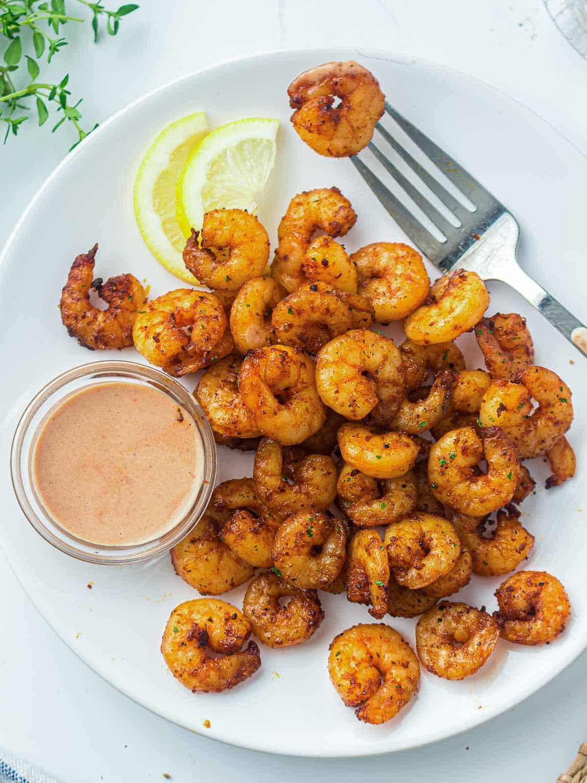 Air fryer shrimp on a white plate served with dipping sauce.