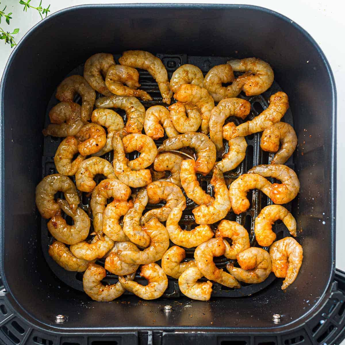 Seasoned shrimp placed in air fryer basket.