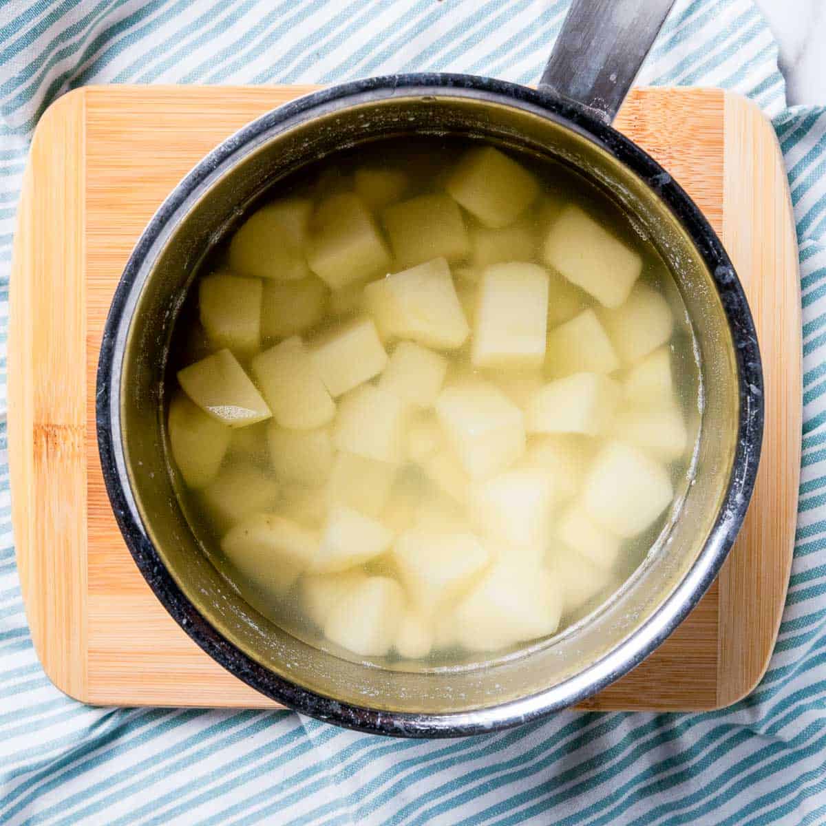 Cubes potatoes boiled in a saucepan.