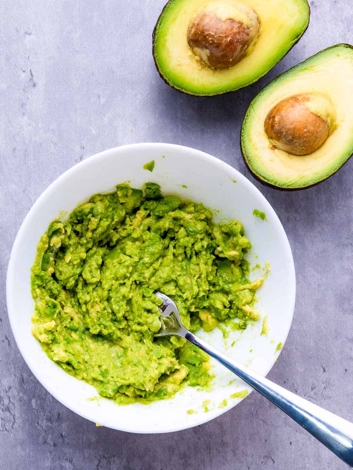 Mashed avocado in a white bowl.