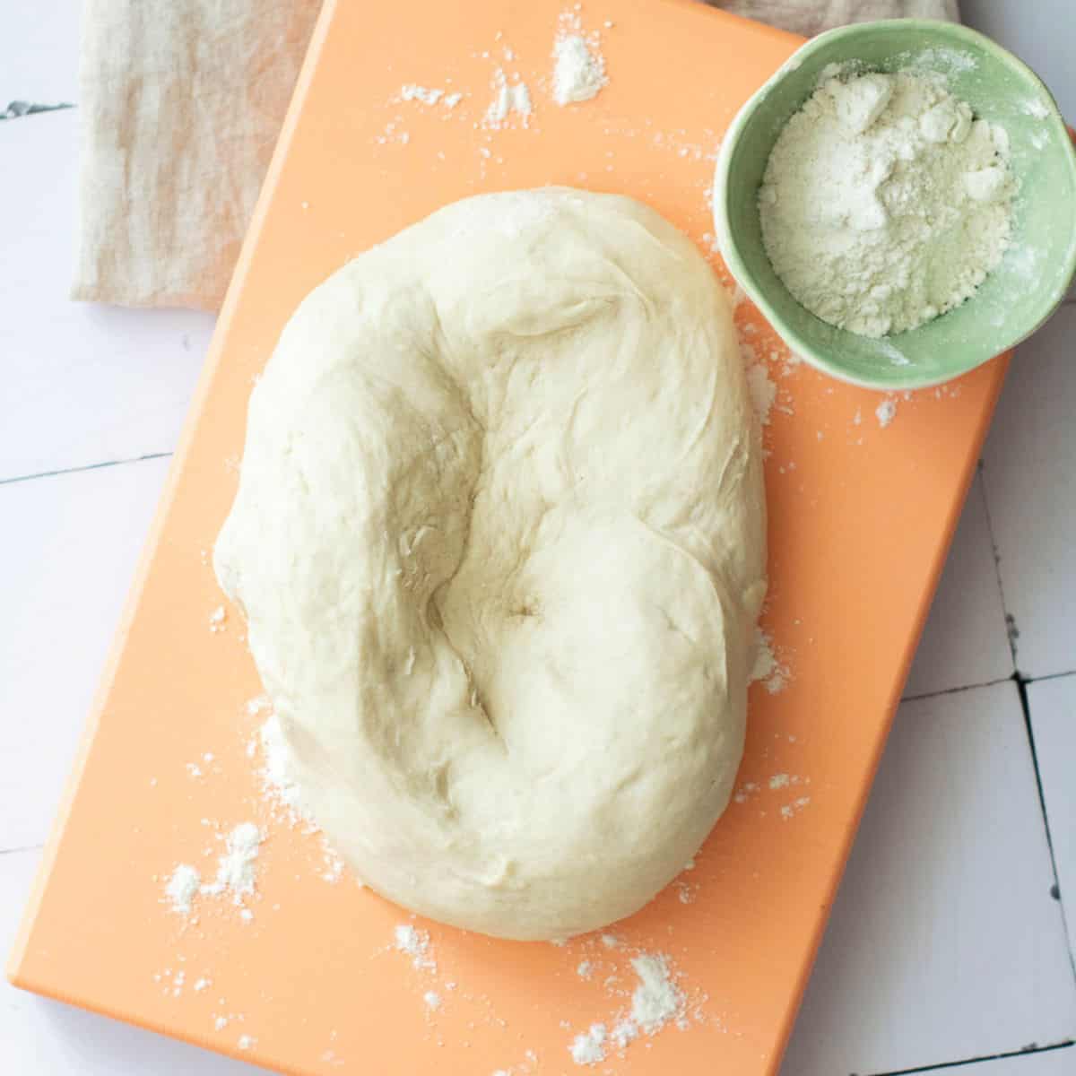 Dough being kneaded on a wooden board.