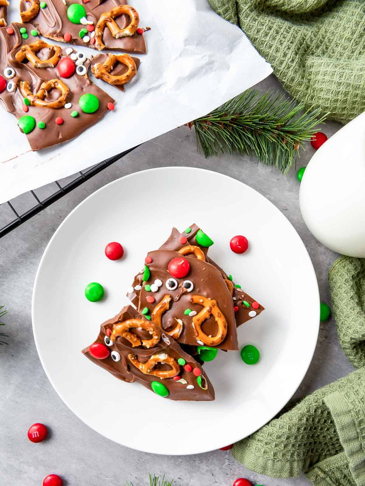 Reindeer chocolate bark on a white plate with milk glass in the background.