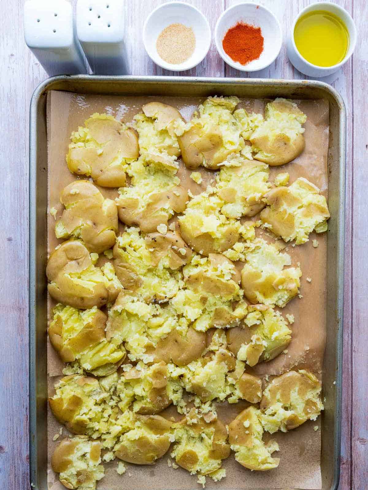 Potatoes smashed on a baking sheet.