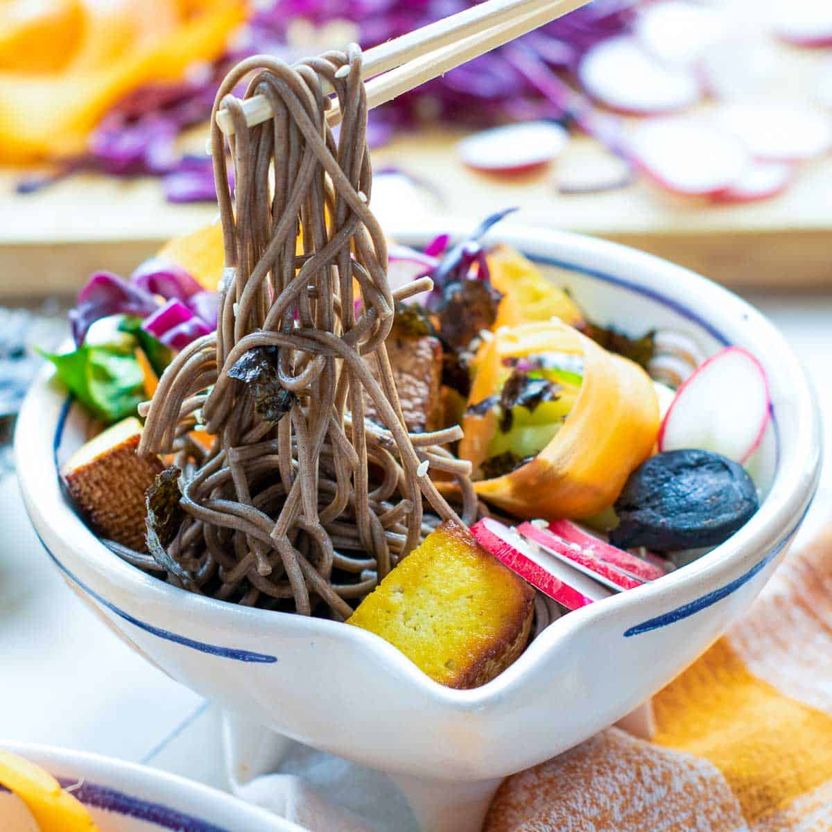 Noodles in chopsticks over the tofu poke bowl.