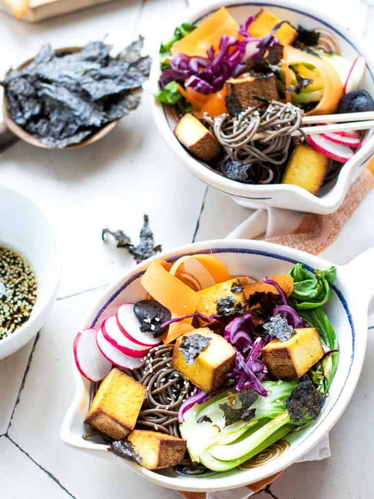 Two assembled smoked tofu poke bowls on a white surface.