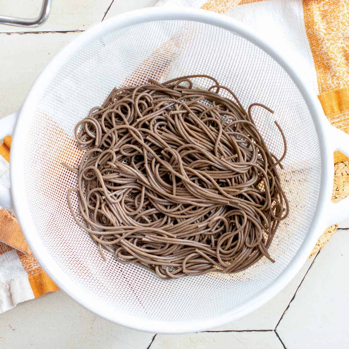 Cooked soba noodles in a strainer.