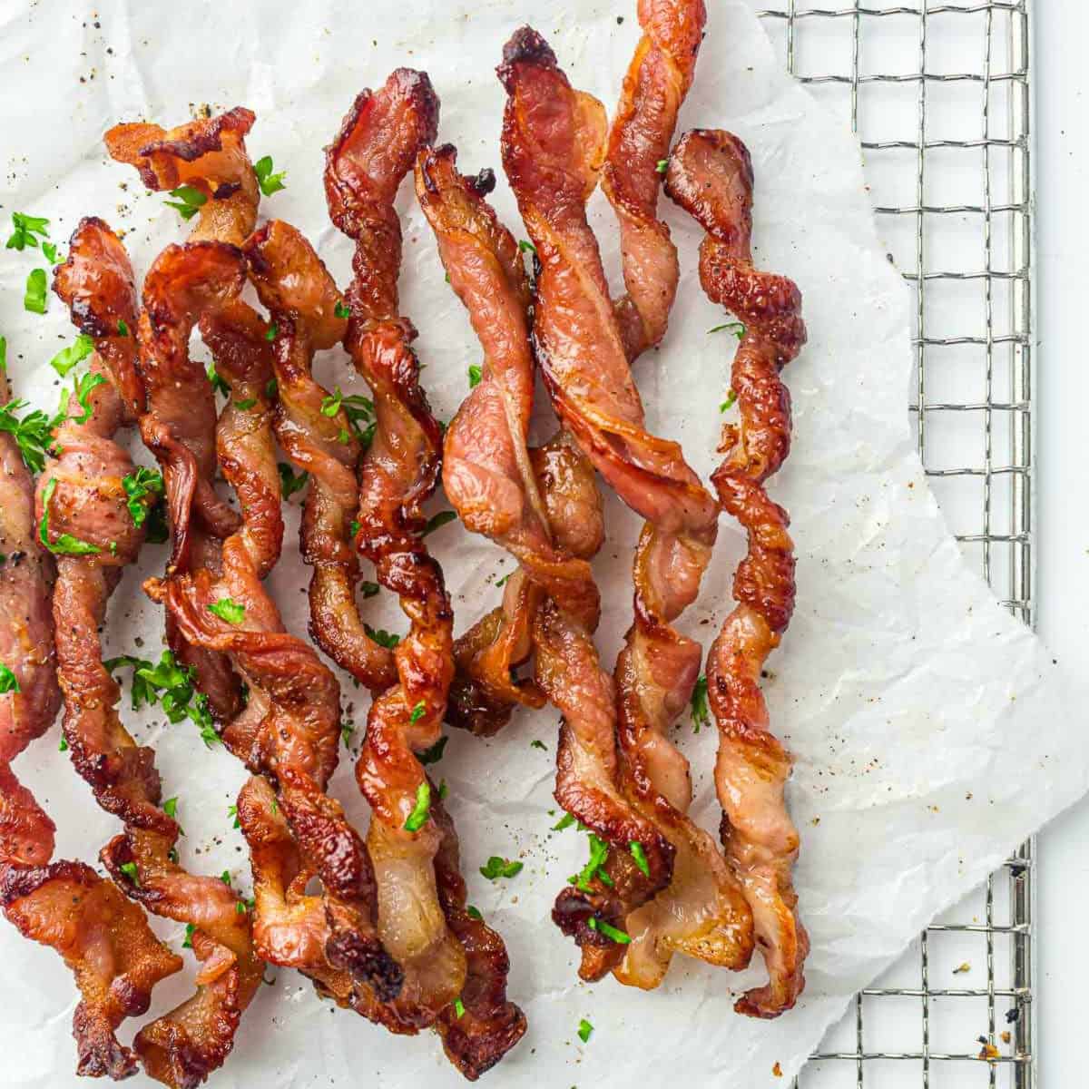 Air fryer twisted bacon on a parchment paper placed on a wire rack.