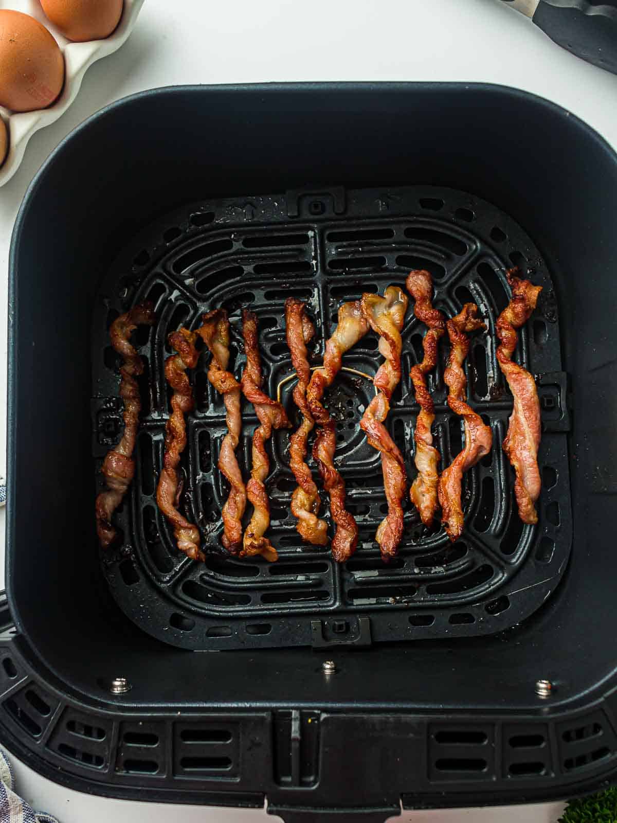 Air fried twisted bacon in an air fryer basket.