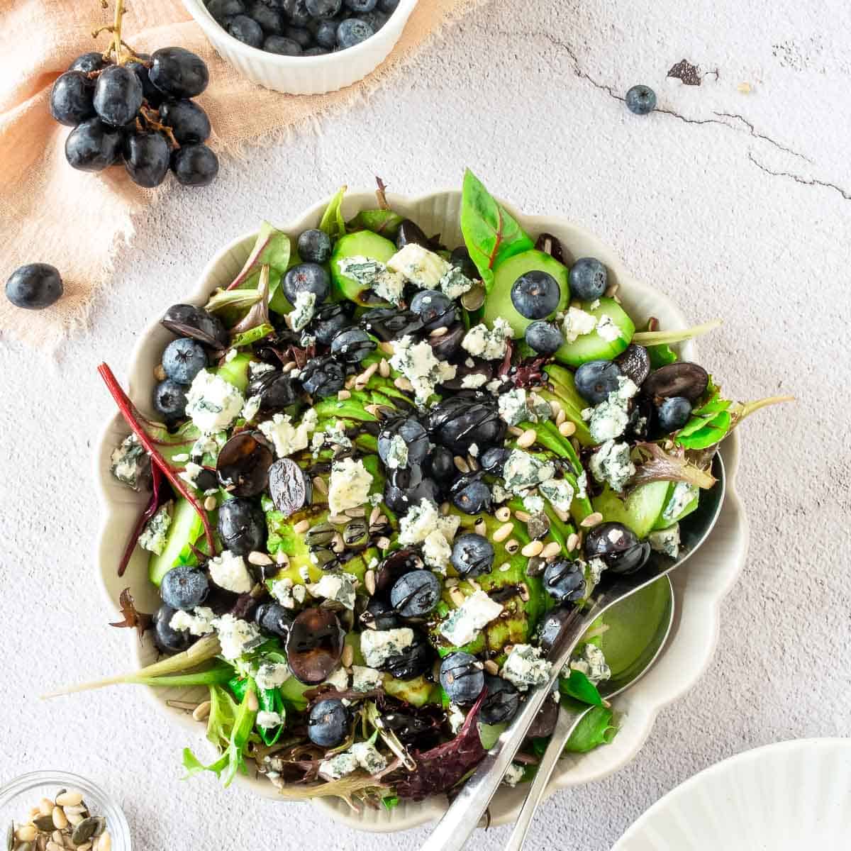 Close up of blueberry grape salad in a white bowl placed on a marble surface.