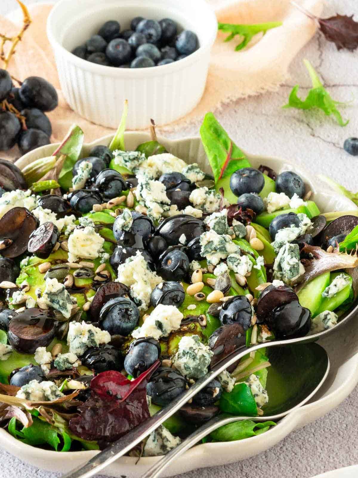 Blueberry grape salad in a wide serving bowl with serving spoons.