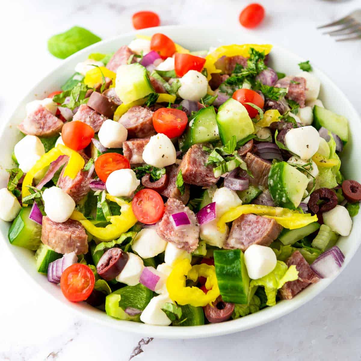 Close up of Italian chopped salad in a wide white bowl.