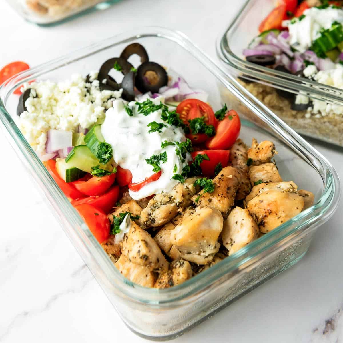 Chicken and toppings over quinoa bed in meal prep containers.